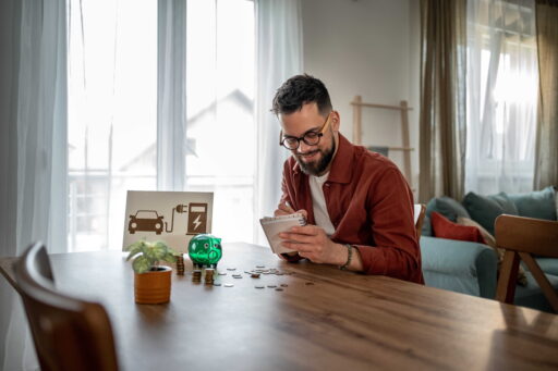 Man Calculating Electric Vehicle Charging Costs and Savings at Home